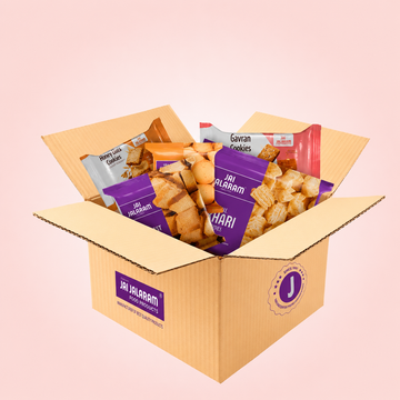 Open cardboard box filled with Jai Jalaram branded snacks on a pink background